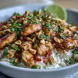 A colorful Thai Peanut Chicken Bowl garnished with cilantro, peanuts, and lime, ready for dinner.