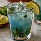 Chilled lavender lemonade infused with fresh mint, a vibrant floral citrus beverage in a glass pitcher, perfect for warm weather entertaining.