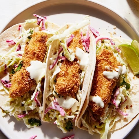 Golden-brown, crispy fish tacos overflowing with vibrant slaw, creamy sauce, and fresh cilantro.