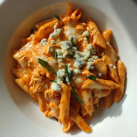 A hearty skillet of Buffalo Chicken Pasta, featuring penne coated in spicy, cheesy sauce with tender chicken.  