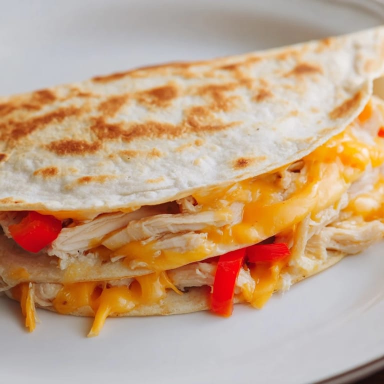 A close-up of a flavorful Chicken Quesadilla, featuring golden-brown tortilla and a delicious melted cheese.