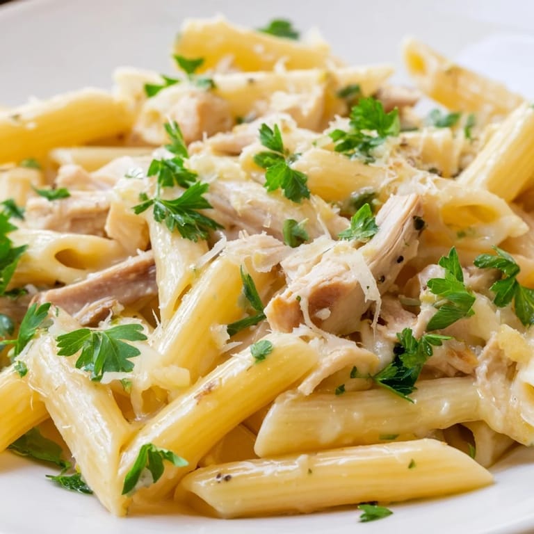 Close-up of Roasted Garlic Chicken Penne showing silky cream sauce coating the ridges of the pasta and tender chicken pieces.