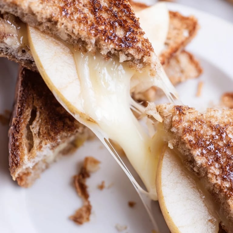 A gourmet smoked Gouda & apple grilled cheese sandwich resting on a wooden board, paired with a steaming bowl of creamy tomato soup for dipping.  