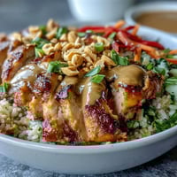 Tender baked chicken, crisp veggies, and creamy peanut sauce top a hearty grain base in this vibrant Peanut Chicken Power Bowl.